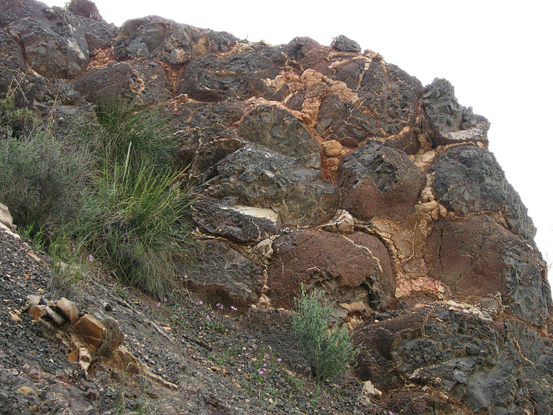 Basalt pillows in Andalusia, Spain, with reddish weathered surfaces. Where parts of the pillows have broken away, darker unweathered basalt is visible. _Source:Ignacio Benvenuty Cabral (2011) CC BY-NC-SA [view source](https://flic.kr/p/9z1V6B)_