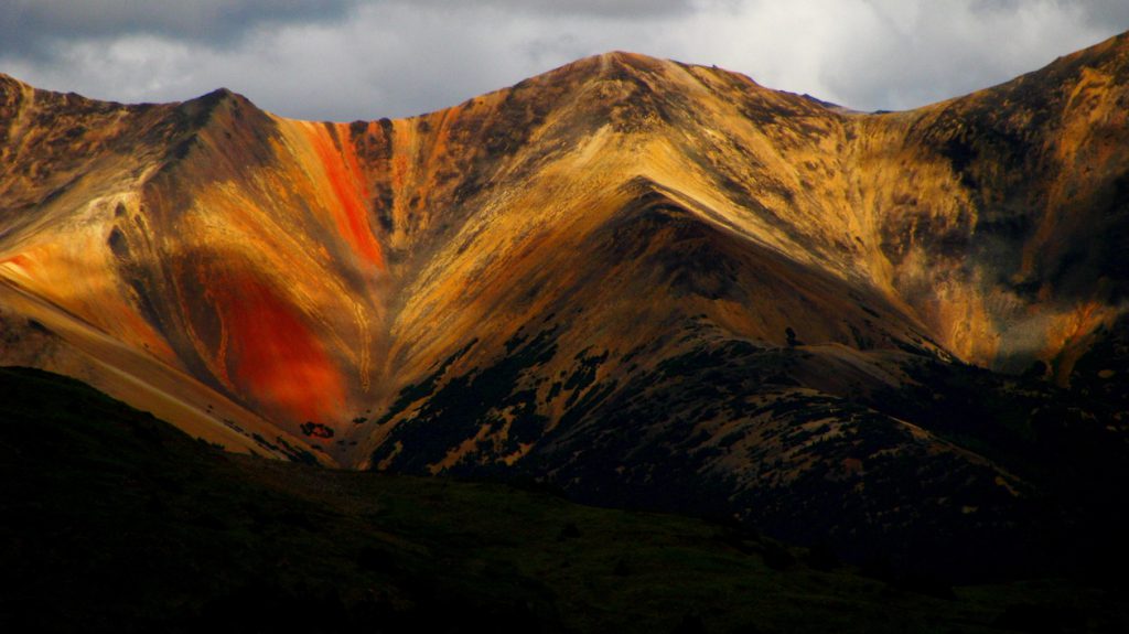 Tsitsutl, the "painted mountain" within the Rainbow Range of the Anahim Volcanic Belt. The vibrant colours of the Rainbow Range are the result of chemical weathering. _Source: Drew Brayshaw (2015) CC BY-NC 2.0 [view source](https://flic.kr/p/wPuhSC)_