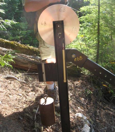 | Part of a motion-monitoring device at the Checkerboard Slide near Revelstoke, BC. The lower end of the cable (extending out from the top of the device to the right) is attached to a block of rock that is unstable. Any incremental motion of this block will move the cable, which will be detectable by this device. _ Source: Steven Earle (2015) CC BY 4.0. [View source](https://opentextbc.ca/geology/) _